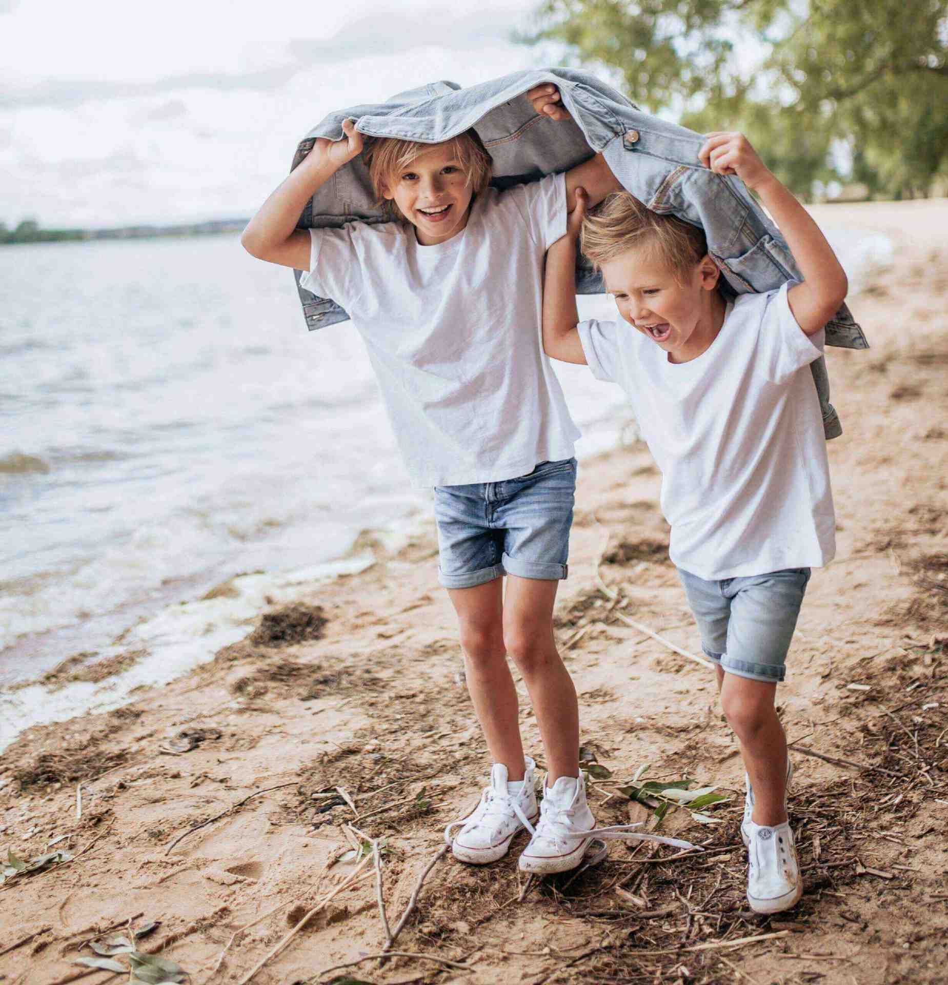 Two boys showing off their smiles near a muddy beach